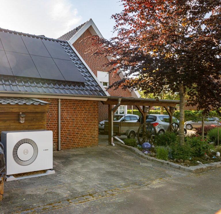 Eine Bosch Wärmepumpe vor einem Wohnhaus mit einer Photovoltaikanlage von Moddemann Neue Energien GmbH